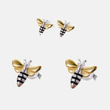Boucles d'oreilles corp de l'abeille en argent les ailes sont plaquées et or thème abeille sur un fond gris clair.